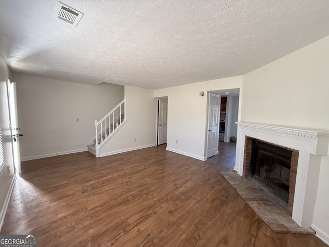 unfurnished living room featuring a brick fireplace, dark hardwood / wood-style floors, and a textured ceiling