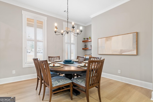 dining space with crown molding, light hardwood / wood-style floors, and an inviting chandelier