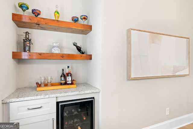 bar featuring white cabinets, light stone counters, and beverage cooler