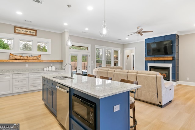 kitchen with pendant lighting, white cabinets, black microwave, french doors, and sink