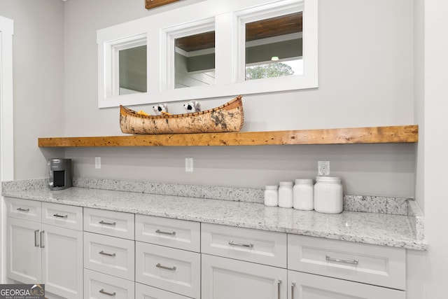 bar featuring white cabinets and light stone countertops