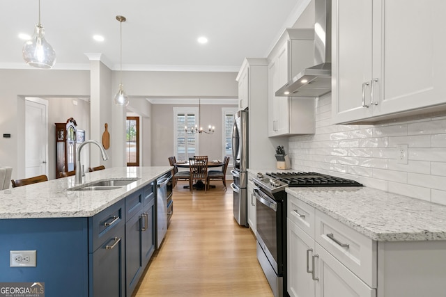 kitchen with white cabinetry, hanging light fixtures, sink, wall chimney range hood, and stainless steel appliances