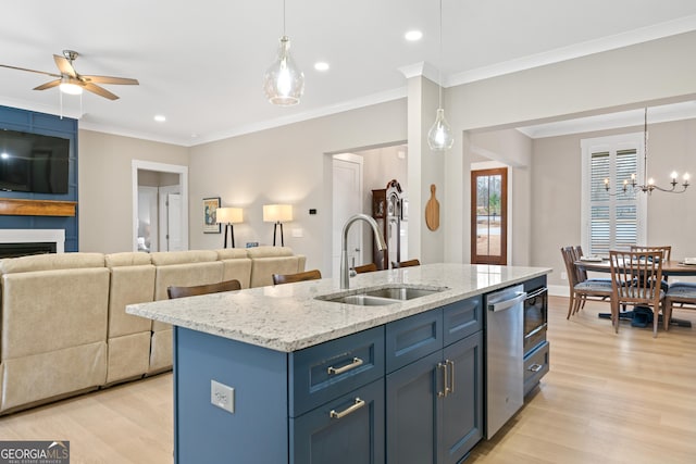 kitchen featuring hanging light fixtures, sink, blue cabinets, a large fireplace, and an island with sink