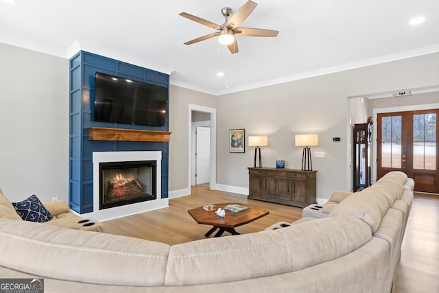 living room with light hardwood / wood-style floors, crown molding, french doors, and a fireplace