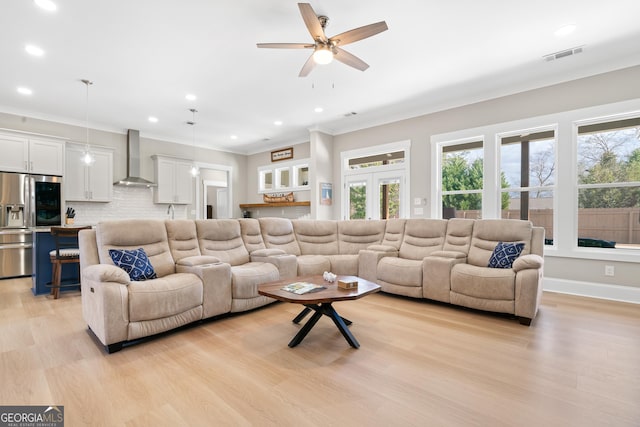 living room featuring ceiling fan, a wealth of natural light, ornamental molding, and light wood-type flooring