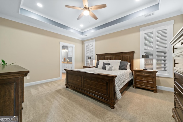 carpeted bedroom with ceiling fan, ensuite bathroom, and a raised ceiling