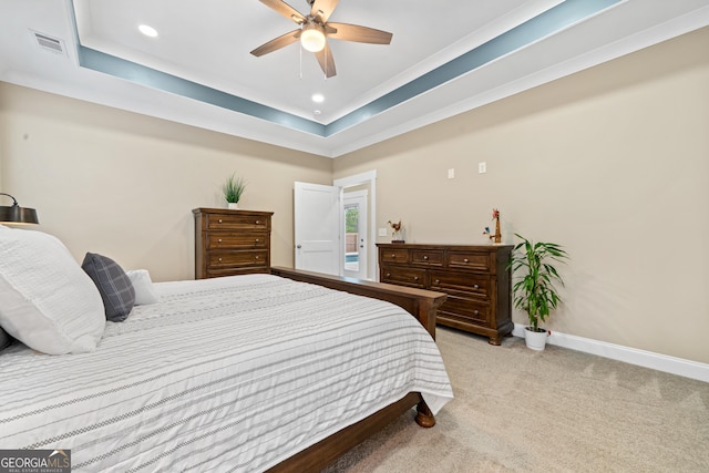 carpeted bedroom with ceiling fan and a tray ceiling