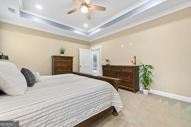 bedroom featuring ceiling fan, a tray ceiling, and light carpet