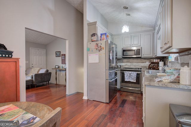 kitchen featuring pendant lighting, appliances with stainless steel finishes, sink, a textured ceiling, and lofted ceiling