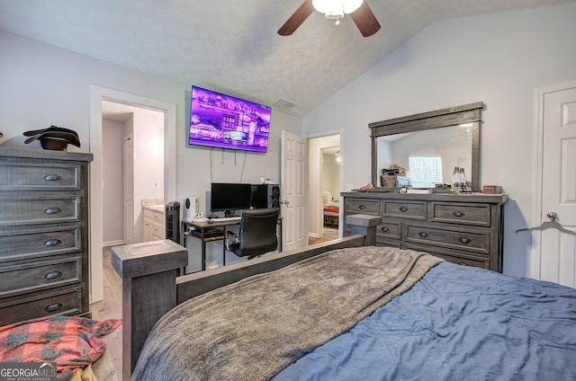 bedroom featuring a textured ceiling, connected bathroom, vaulted ceiling, and ceiling fan