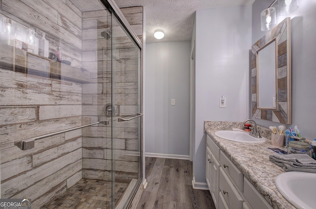 bathroom featuring vanity, a shower with shower door, hardwood / wood-style floors, and a textured ceiling