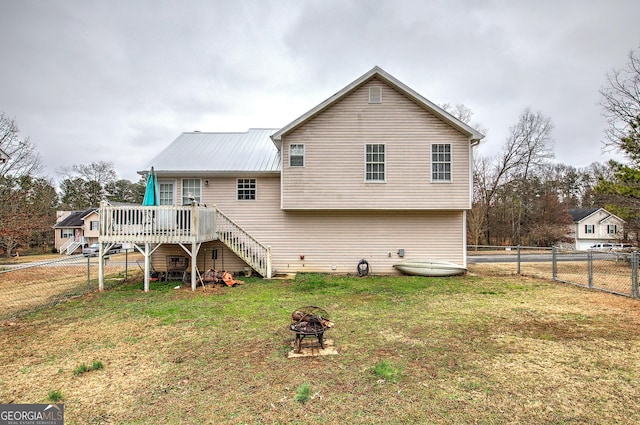 back of house featuring a deck, a lawn, and a fire pit