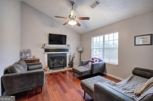 living room with vaulted ceiling, ceiling fan, dark hardwood / wood-style floors, and a textured ceiling