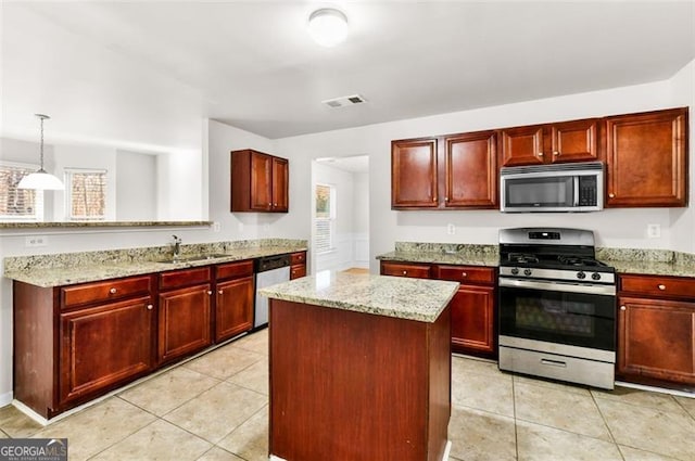 kitchen with pendant lighting, light stone counters, appliances with stainless steel finishes, and sink