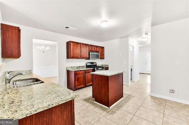 kitchen with light stone countertops, stainless steel appliances, sink, kitchen peninsula, and light tile patterned floors