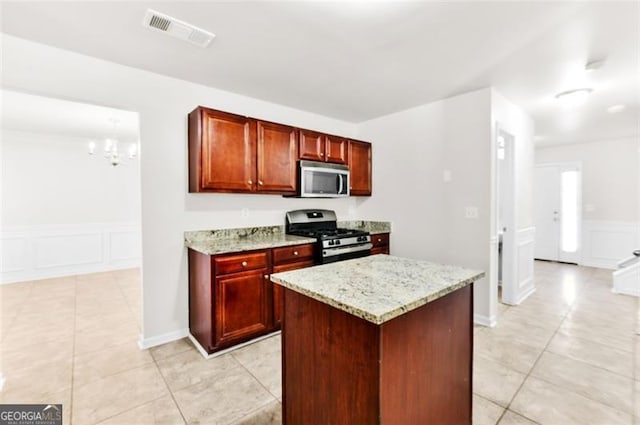 kitchen featuring light stone countertops, a center island, stainless steel appliances, a chandelier, and light tile patterned floors