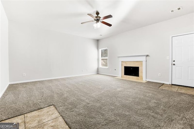 unfurnished living room featuring ceiling fan, carpet floors, and a tiled fireplace