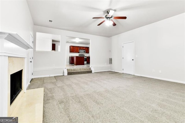 unfurnished living room with a premium fireplace, ceiling fan, and light carpet