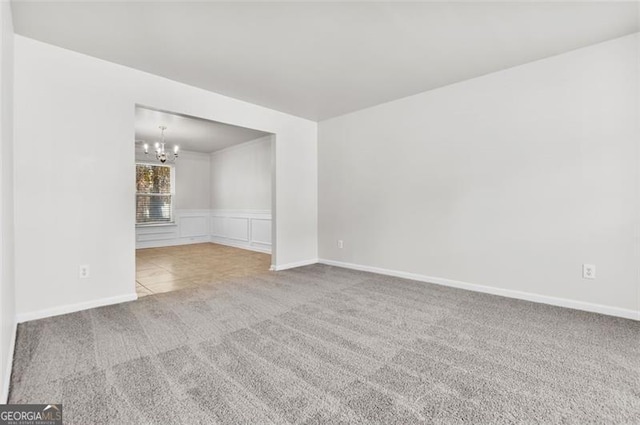 carpeted empty room featuring a chandelier