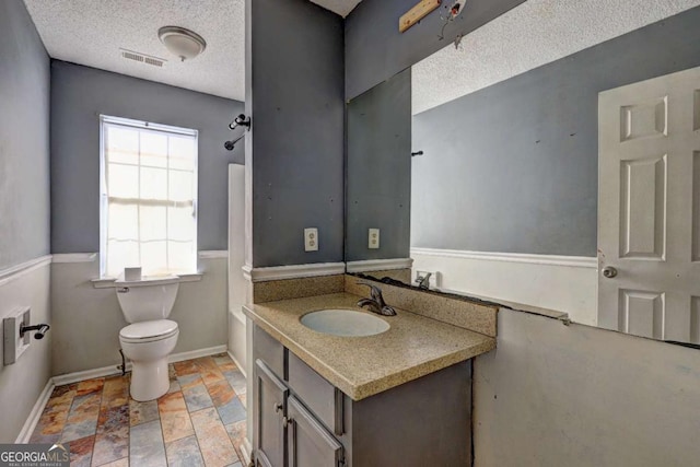 bathroom with a textured ceiling, toilet, and vanity