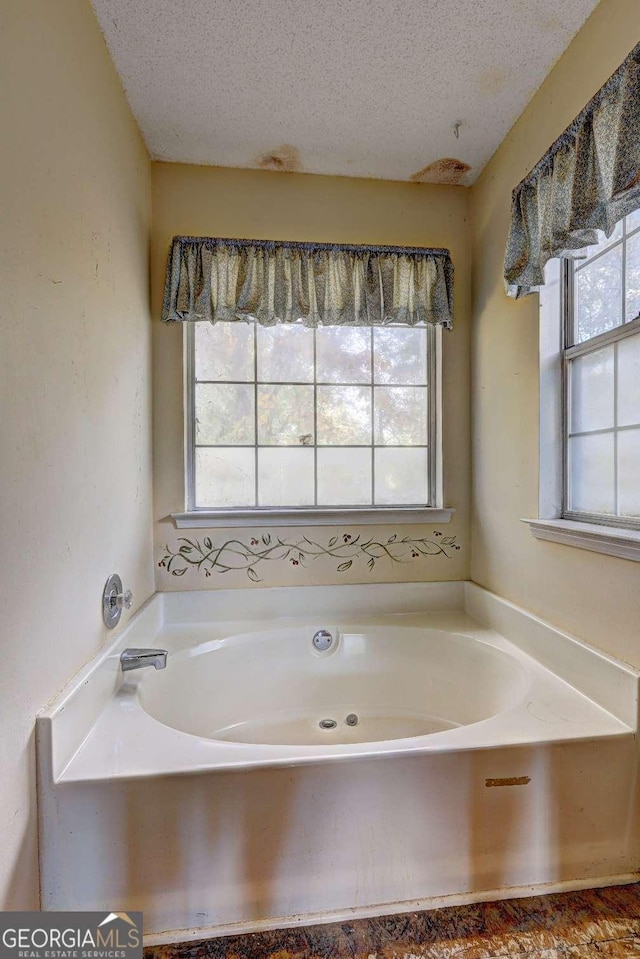 bathroom featuring a tub and a textured ceiling