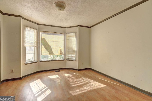 unfurnished room featuring a textured ceiling, light hardwood / wood-style flooring, and crown molding