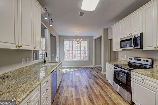 kitchen featuring sink, white cabinetry, appliances with stainless steel finishes, and hanging light fixtures