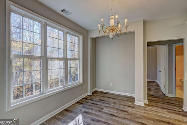 unfurnished dining area featuring hardwood / wood-style floors and a notable chandelier