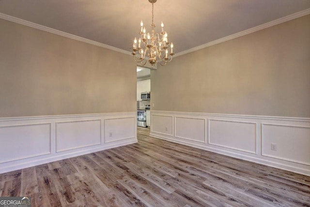 unfurnished room with an inviting chandelier, light hardwood / wood-style floors, and crown molding