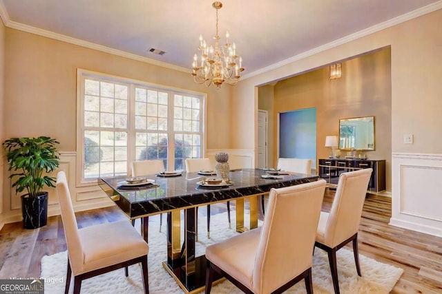 dining space featuring light wood-type flooring, a chandelier, and ornamental molding