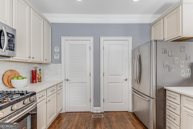 kitchen featuring dark wood-style flooring, stainless steel appliances, light countertops, and ornamental molding