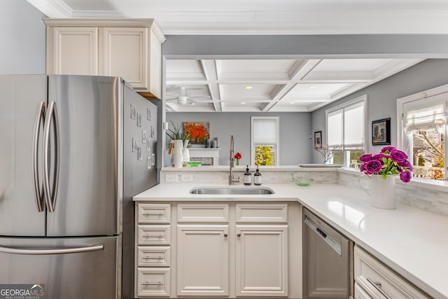 kitchen with beamed ceiling, light countertops, appliances with stainless steel finishes, coffered ceiling, and a sink