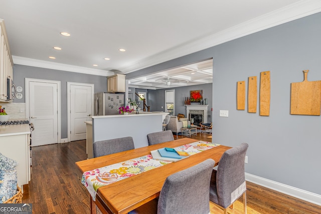 dining space with baseboards, dark wood finished floors, recessed lighting, a glass covered fireplace, and coffered ceiling