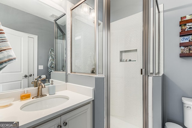 bathroom with vanity, a shower stall, and toilet