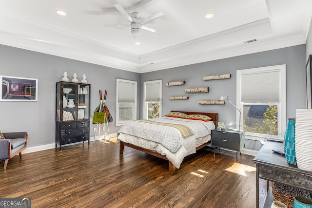 bedroom with visible vents, baseboards, ornamental molding, wood finished floors, and a raised ceiling