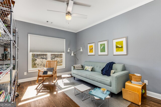 living room featuring visible vents, baseboards, wood finished floors, and ornamental molding