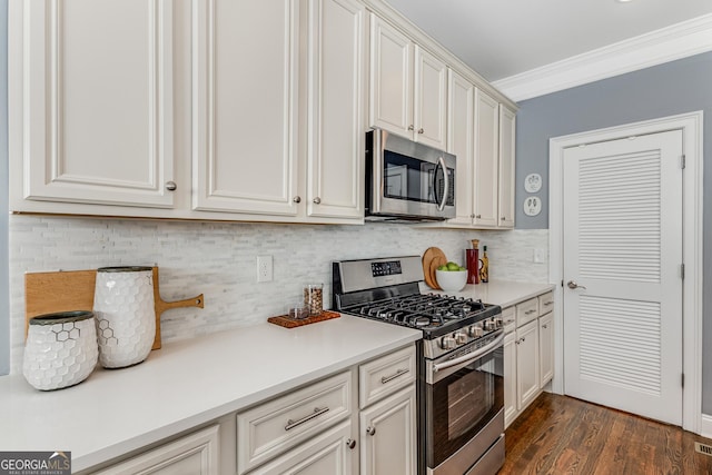 kitchen with tasteful backsplash, dark wood finished floors, appliances with stainless steel finishes, crown molding, and light countertops