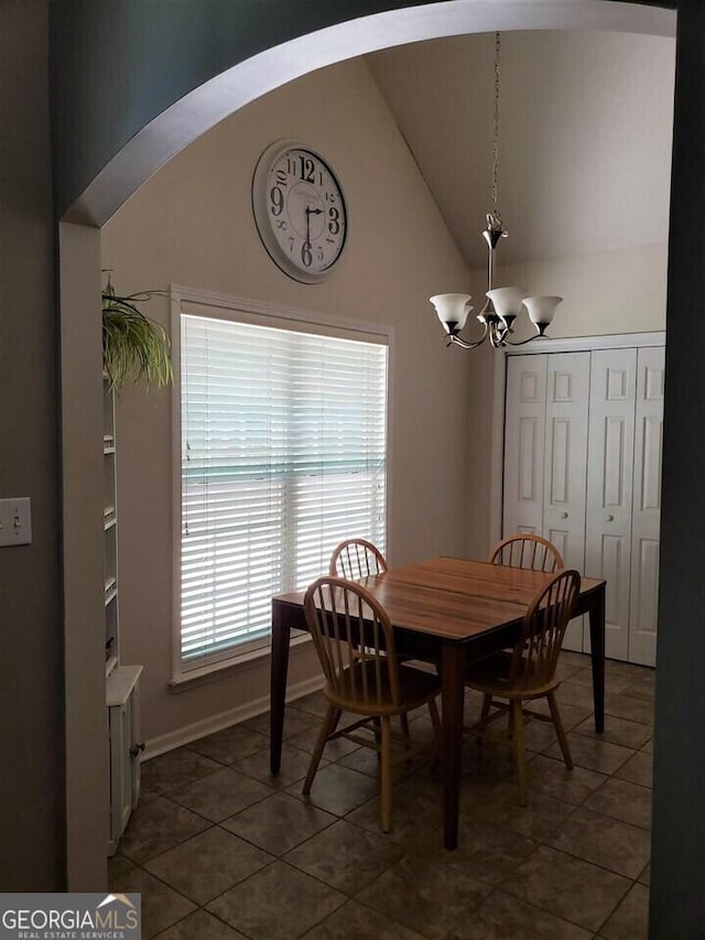 dining area with an inviting chandelier, high vaulted ceiling, and dark tile patterned floors