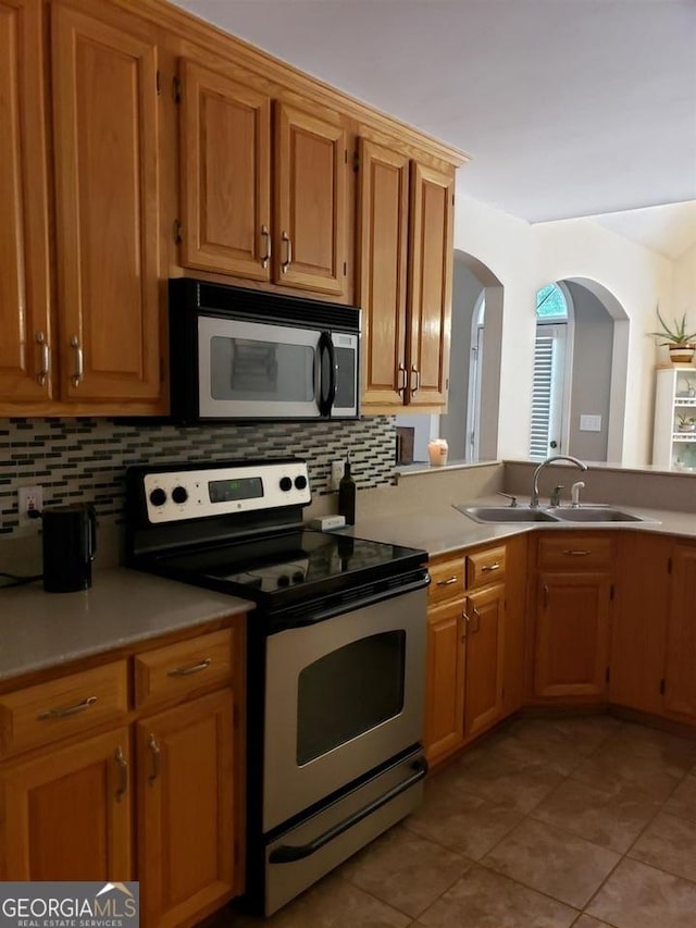 kitchen featuring sink, stainless steel electric stove, tasteful backsplash, and light tile patterned flooring