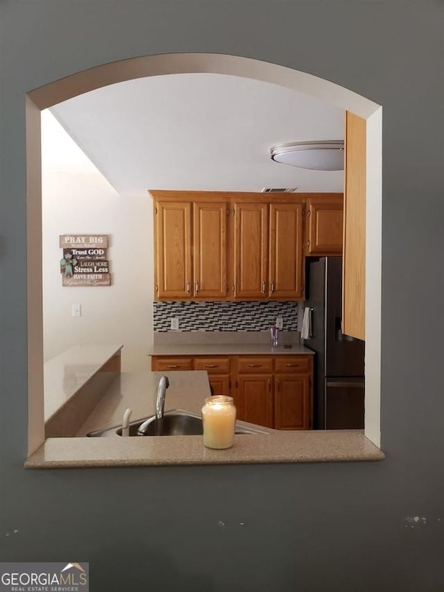 kitchen with sink, backsplash, and black fridge