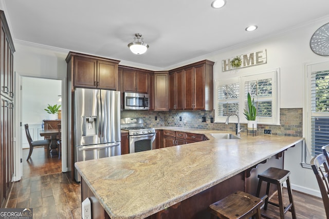 kitchen with sink, ornamental molding, kitchen peninsula, stainless steel appliances, and dark wood-type flooring