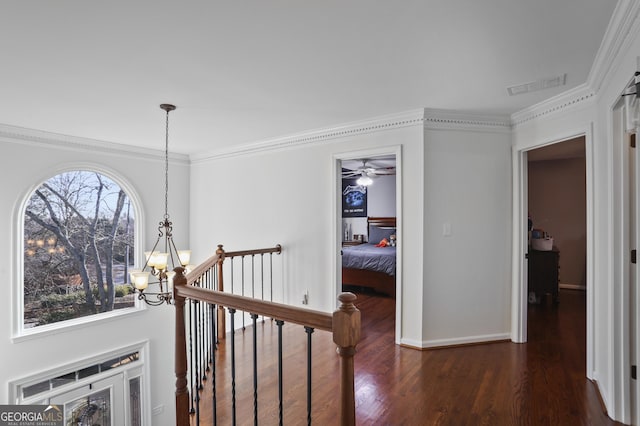 corridor with ornamental molding, dark hardwood / wood-style floors, and a chandelier