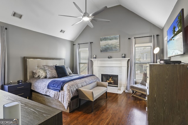 bedroom with lofted ceiling, dark wood-type flooring, a fireplace, and ceiling fan