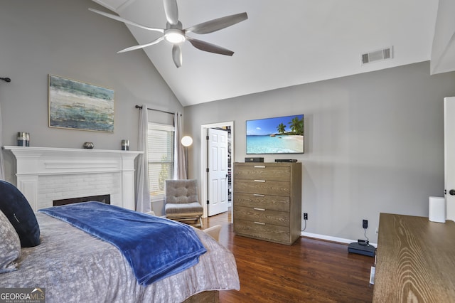 bedroom featuring ceiling fan, dark hardwood / wood-style flooring, high vaulted ceiling, and a brick fireplace