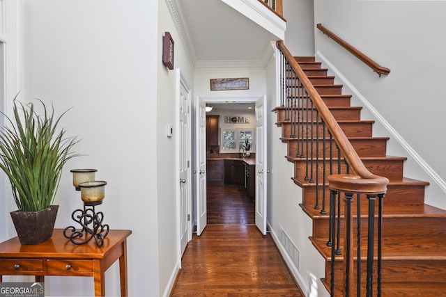 staircase featuring ornamental molding, wood-type flooring, and sink