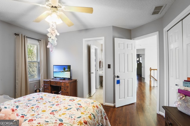 bedroom featuring dark wood-type flooring, a textured ceiling, ceiling fan, and a closet