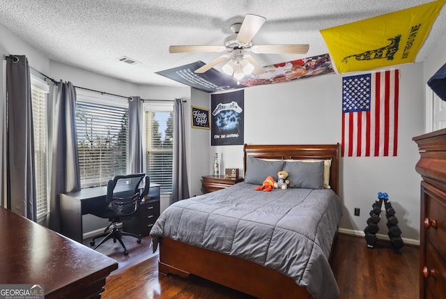 bedroom with a textured ceiling, dark wood-type flooring, and ceiling fan