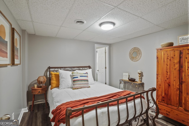 bedroom with dark wood-type flooring and a paneled ceiling