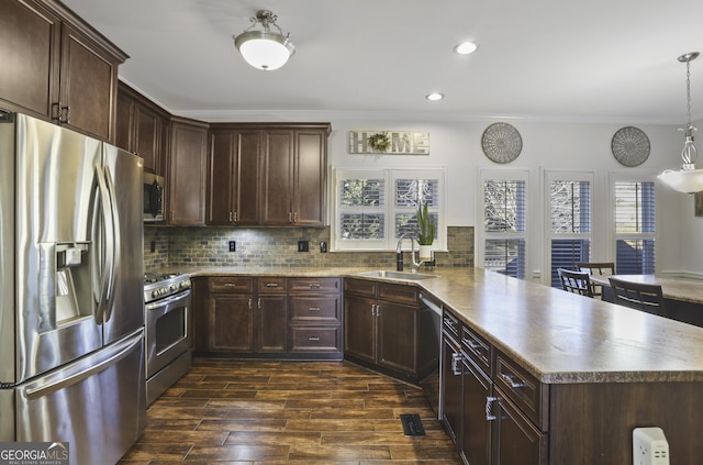 kitchen with sink, hanging light fixtures, appliances with stainless steel finishes, ornamental molding, and decorative backsplash