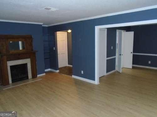 unfurnished living room with hardwood / wood-style floors and ornamental molding